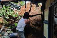 Seorang warga membantu membersihkan puing rumah yang hancur akibat tanah longsor di Kelurahan Remu Selatan, Kecamatan Sorong Manoi, Kota Sorong, Papua Barat, Sabtu (19/9)