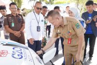 Sekretaris Daerah Kabupaten Kuala Kapuas, Septedy, (membungkuk) melakukan pengisian daya mobil listrik menggunakan SPKLU.