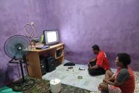 Billy Guraray (38), salah satu masyarakat Kampung Pasir Putih, Distrik Fkour menikmati tayang televisi secara nyaman dengan hadirnya listrik PLN selama 24 jam