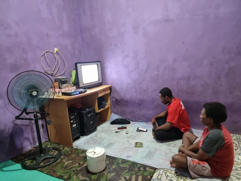 Billy Guraray (38), salah satu masyarakat Kampung Pasir Putih, Distrik Fkour menikmati tayang televisi secara nyaman dengan hadirnya listrik PLN selama 24 jam