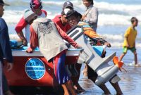 Nelayan di Pantai Teluk Penyu, Cilacap gotong royong mendorong kapal bermesin listrik untuk digunakan mencari ikan.