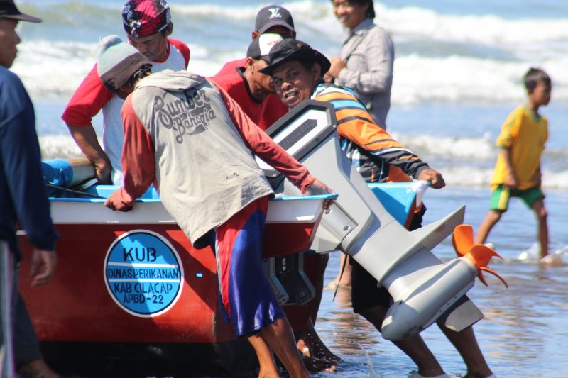 Nelayan di Pantai Teluk Penyu, Cilacap gotong royong mendorong kapal bermesin listrik untuk digunakan mencari ikan.