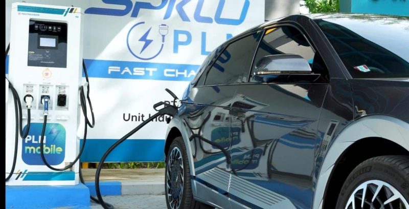 lustrasi pengisian kendaraan listrik di Stasiun Pengisian Kendaraan Listrik Umum (SPKLU) PLN yang memudahkan pemilik kendaraan mobil listrik. Infrastruktur SPKLU sudah tersebar di seluruh wilayah Indonesia dan untuk mengetahui lokasi SPKLU terdekat dapat dilihat pada aplikasi PLN Mobile.