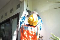 Ilustrasi petugas PLN saat melakukan penambahan daya pada kWh meter milik pelanggan.