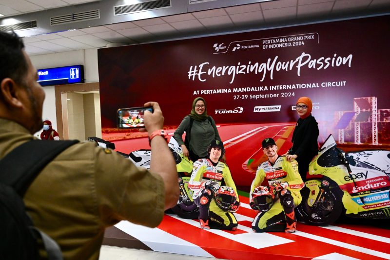 Keterangan Foto 1: Antusias wisatawan saat berfoto di spot foto unik dengan papan menyerupai pembalap Tim VR46 MotoGP yang ada di Bandara Internasional Lombok. Selasa (24/9/2024).
