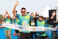 Direktur Utama PLN, Darmawan Prasodjo (kiri) bersama istri, Diny Darmawan Prasodjo (kanan) saat melintasi garis finish dan menyelesaikan PLN Electric Run 2024 kategori 5K.