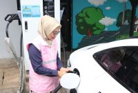 Estuning Rahayu ketika membantu mengisi daya kendaraan listrik milik pelanggan pada periode arus balik mudik lebaran 1446 H.
