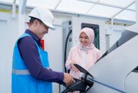 Ilustrasi pengguna electric vehicle dibantu oleh Petugas PLN ketika mengisi kendaraan listriknya di SPKLU.