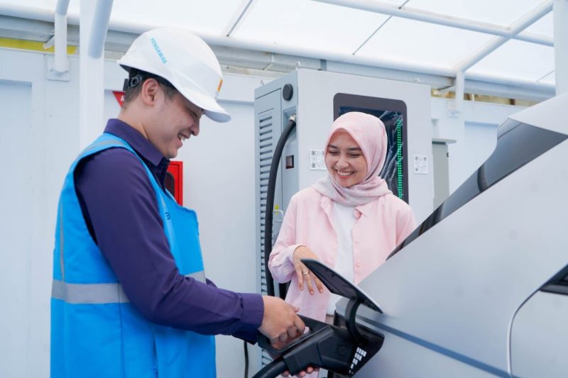 Ilustrasi pengguna electric vehicle dibantu oleh Petugas PLN ketika mengisi kendaraan listriknya di SPKLU.