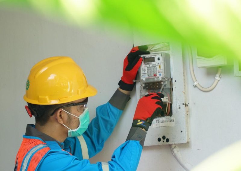 Ilustrasi petugas PLN saat menambah daya pada kWh meter pelanggan. Program diskon tambah daya menjadi bagian dari strategi intensifikasi PLN dalam mengoptimalkan konsumsi listrik pelanggan eksisting. Strategi ini menyumbang 5,80 TWh terhadap pertumbuhan penjualan listrik di tahun 2024.