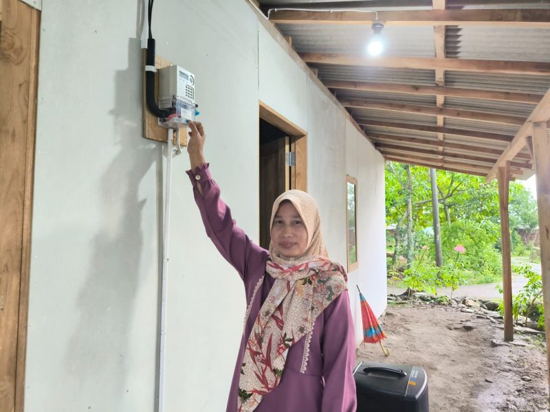 Karmini, warga Desa Ngandul, Kabupaten Sragen, Jawa Tengah di depan meter listrik miliknya sendiri, bantuan pemasangan listrik gratis dari PLN. Kini ia bisa menikmati listrik secara mandiri tanpa harus menumpang lagi.