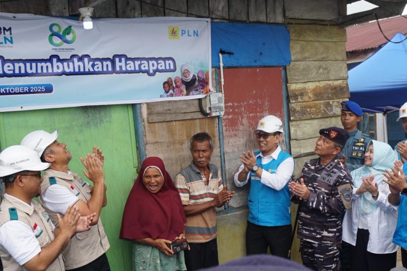 Momen penyalaan sambungan listrik program “Berbagi Cahaya, Menumbuhkan Harapan” oleh Direktur Manajemen Risiko PLN, Adi Lumakso (ketiga dari kanan), di rumah salah satu penerima manfaat, Nazaruddin (tengah). Rasa haru dan bahagia terpancar dari pasangan suami istri ini saat rumah mereka akhirnya memiliki sambungan listrik mandiri.