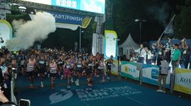 Direktur Utama PLN, Darmawan Prasodjo (belakang memegang bendera) bersama jajaran Direksi dan Komisaris PLN melepas para peserta Kategori Half Marathon PLN Electric Run 2025 di garis start.