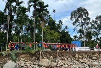 Sejumlah petugas PLN bahu-membahu memikul tiang jaringan listrik secara manual untuk menembus wilayah yang terisolir akibat bencana. Meskipun terdapat 171 titik longsor yang memutus akses jalan darat, PLN terus berupaya mempercepat pemulihan infrastruktur kelistrikan di 68 desa tersisa.