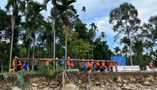 Sejumlah petugas PLN bahu-membahu memikul tiang jaringan listrik secara manual untuk menembus wilayah yang terisolir akibat bencana. Meskipun terdapat 171 titik longsor yang memutus akses jalan darat, PLN terus berupaya mempercepat pemulihan infrastruktur kelistrikan di 68 desa tersisa.