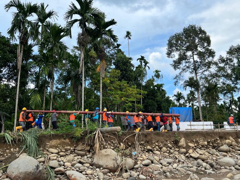 Sejumlah petugas PLN bahu-membahu memikul tiang jaringan listrik secara manual untuk menembus wilayah yang terisolir akibat bencana. Meskipun terdapat 171 titik longsor yang memutus akses jalan darat, PLN terus berupaya mempercepat pemulihan infrastruktur kelistrikan di 68 desa tersisa.