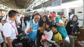 Direktur Legal dan Manajemen Human Capital PLN, Yusuf Didi Setiarto saat melakukan swafoto bersama salah satu keluarga yang menjadi peserta Mudik Gratis BUMN sebelum diberangkatkan dari Stasiun Pasar Senen, Jakarta pada Selasa (17/3).