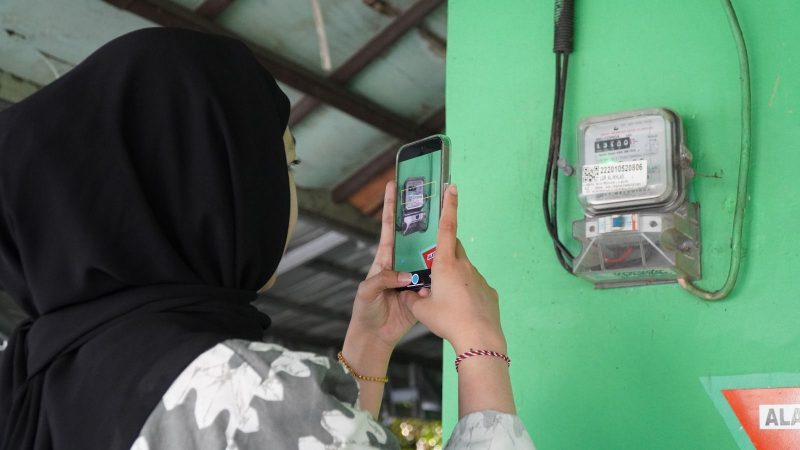 Ilustrasi pelanggan tengah memanfaatkan fitur SwaCAM di aplikasi PLN Mobile untuk mencatat stand meter listrik secara mandiri pada tanggal 23 hingga 27 setiap bulannya. Fitur ini memudahkan pelanggan pascabayar dalam memantau pemakaian listrik dan memperkirakan tagihan dengan lebih jelas.