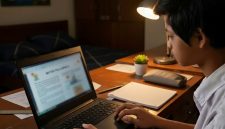 Ilustrasi seorang anak sedang fokus mengerjakan tugas menggunakan laptop di kamarnya pada malam hari.